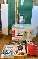 Full lot showing sewing machine box, cutting mat, quilting ruler, and books