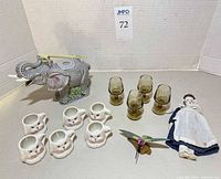 Overall lot showing elephant teapot, bunny cups, glass goblets, porcelain doll, wooden hummingbird