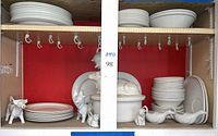 Full cabinet view with stacked dinnerware, platters and animal gravy boats