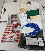 Entire lot overview showing multiple packaged and loose table linens, napkin rings, and booklet