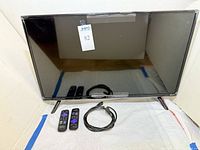 Front view of 32-inch Westinghouse Roku TV with two remotes and HDMI cable displayed