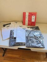 Eight individually bagged Karen Scott tops and packaged scarf displayed on table