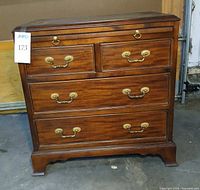 Front view showing all four drawers closed, brass pulls, overall finish and bracket feet