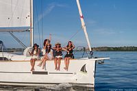 Women seated on bow of sailboat underway on calm water