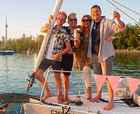 Group holding drinks on sailboat with Toronto skyline and CN Tower in background