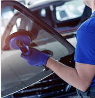 Technician using suction tool on car windshield