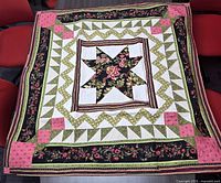Full view of quilt laid flat showing patchwork pattern, borders, overall colour scheme