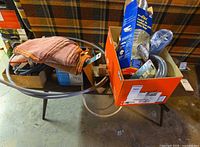 Overall lot on table with orange box showing dryer vent duct, hoses and towel bar