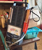 Handheld battery load tester showing vented body, handle and clamps