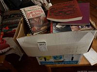 Box with spiral cookbook Homestead Tested Recipes, Wokcraft book, other cookbooks piled
