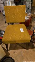 Front view of mustard fabric dining chair showing square back, seat, single button tuft, wooden legs, condition wear