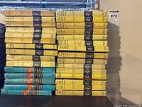Two stacks of yellow and blue Grosset & Dunlap hardcover Nancy Drew and Hardy Boys books