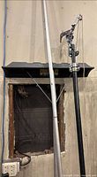 Silver aluminum roof rake and black pole branch trimmer leaning against wall