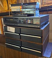 Sony SL-100 VCR stacked on cabinet with remote visible on top and six blank Betamax tapes