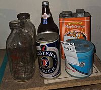 Group shot of all containers: syrup tin, Player's tin, Foster's can, Pabst bottle, two milk bottles