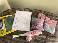 All items laid out: board with markers and eraser, template insert, craft lacing strands, Strawberry Shortcake bat & ball