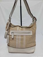 Front view of Coach khaki signature stripe duffle bag showing front zip pocket, tassels, overall condition