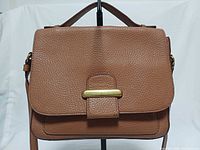 Front view of Fossil Tatum brown leather crossbody bag showing flap and brass bar closure