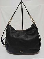 Front view of black pebbled leather Kate Spade bag showing shape, texture, hardware and handles