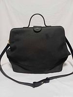 Front view of black canvas Kate Spade Saturday satchel with top handle and shoulder strap