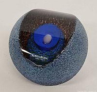 Front view showing textured blue exterior, polished facet, internal motif, label visible