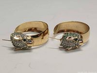 Front view of both gold-plated hoop earrings showing panther heads with rhinestones and green eyes