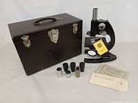 Full lot showing microscope, case, accessories and booklets