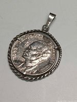 Front of pendant showing coin obverse in rope bezel with bail