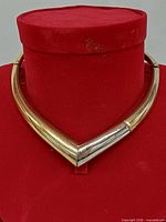 Front view of V-shaped gold and silver-tone collar necklace on display bust