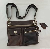 Front view showing pockets, strap, hardware, charm