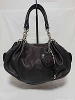 Front view of black leather hobo handbag with heart mirror charm