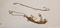 Tangled group of two silvertone chain necklaces showing charms and tags