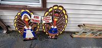 Both wooden turkey decorations leaning against siding