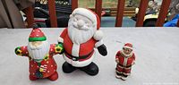Three Santa figurines grouped on tabletop displaying relative sizes and design details