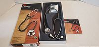 Stethoscope in foam insert beside branded box and booklet