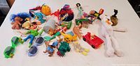 Overview of entire lot of assorted toys laid on white surface