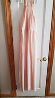Front view of peach maxi dress hanging on door