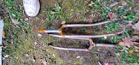 Two rusty steel bicycle fork assemblies on ground