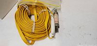 Full view of coiled yellow cable with fuse and connector