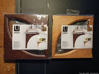 Front view showing both sealed Umbra Brace shelf bracket packages, brown and natural finishes