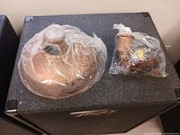 Fixture shade wrapped in plastic and separate bag containing chain and hardware