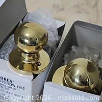 Two boxed polished brass door knob sets showing exterior knobs