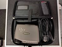 Projector, power cable and remote in open carrying case