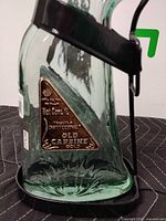 Side view showing tinted bottle in metal stand and gold label