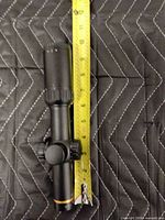 Full view of black 1-6x24 scope next to tape measure