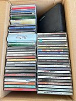 Open box showing two stacks of CD jewel cases and a black CD wallet