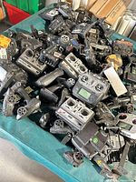 Pile of assorted RC transmitters showing quantity and varied models