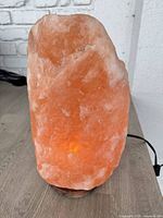Front view of lit Himalayan salt lamp on wood base