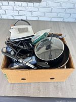 Overview of box with irons, cookware and hair appliances