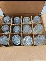 12 glass salt shakers stored upside down in carton divider
